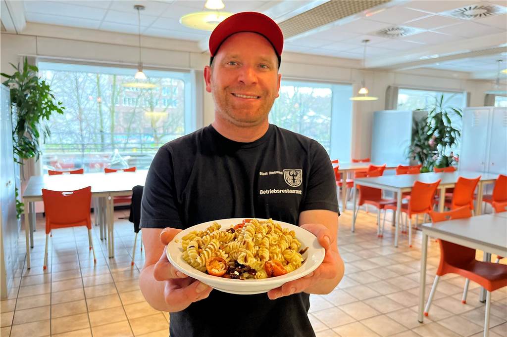 Ein Angestellter der Stadt-Kantine präsentiert eines der Tagesgerichte im Gastraum des städtischen Betriebsrestaurants.