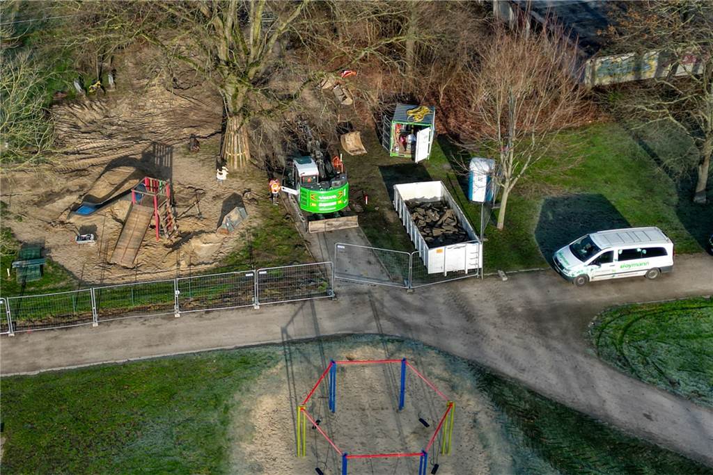 Bauarbeiten hinter dem Hallenbad sind Vorboten des Super-Spielplatzes Ein Bagger fährt entlang des Weges auf der Spielfläche hinter dem Hallenbad. Hier soll unter anderem eine Matschbahn entstehen.