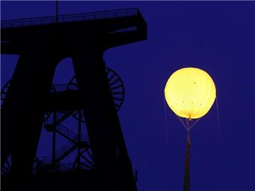 Ein beleuchteter gelber Gasballon über dem Förderturm der ehemaligen Zeche Lohberg in Dinslaken.