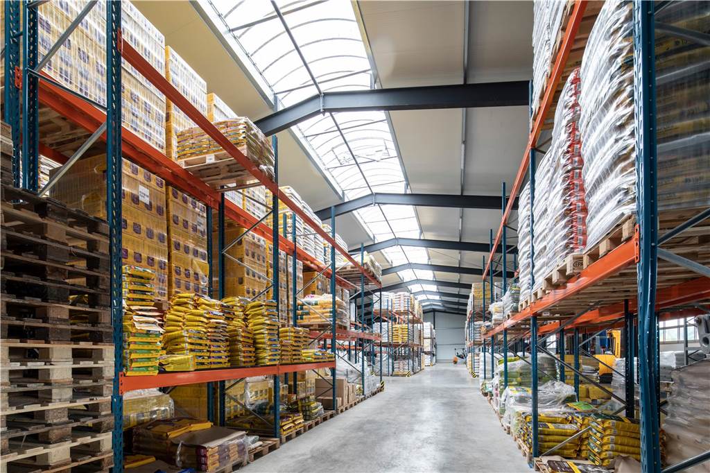 Firmengründung kein Aprilscherz: Rensing Landservice setzt auf Region Ein Blick in eine Lagerhalle an der Robert-Bosch-Straße in Südlohn mit vielen Regalen, Paletten und Säcken.