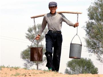 Ein chinesischer Bauer trägt Wasser nach Hause: China will die Schere zwischen Arm und Reich wieder verkleinern. Foto: Michael Reynolds/Archiv