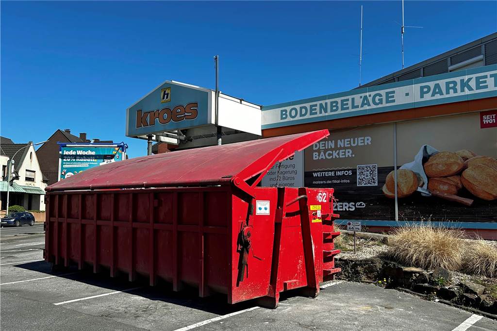 Neuer Eröffnungstermin im Juni für Malzers: Baugenehmigung erst jetzt erhalten Ein roter Container steht vor dem ehemaligen Tapetenhaus Kroes.