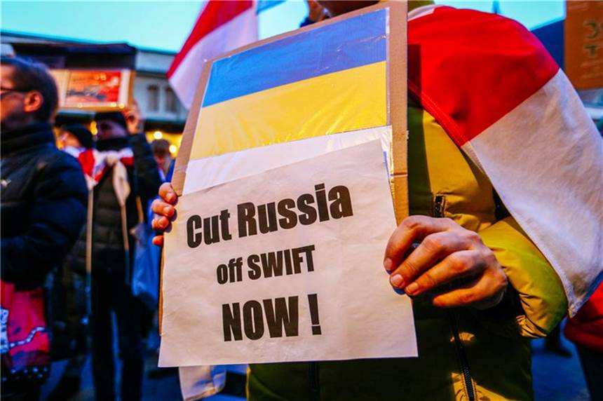 Swift-Ausschluss Russlands: Was heißt das konkret? Ein Demonstrant hält ein Schild mit der ukrainischen Flagge und der Aufschrift „Russland jetzt abschneiden!".