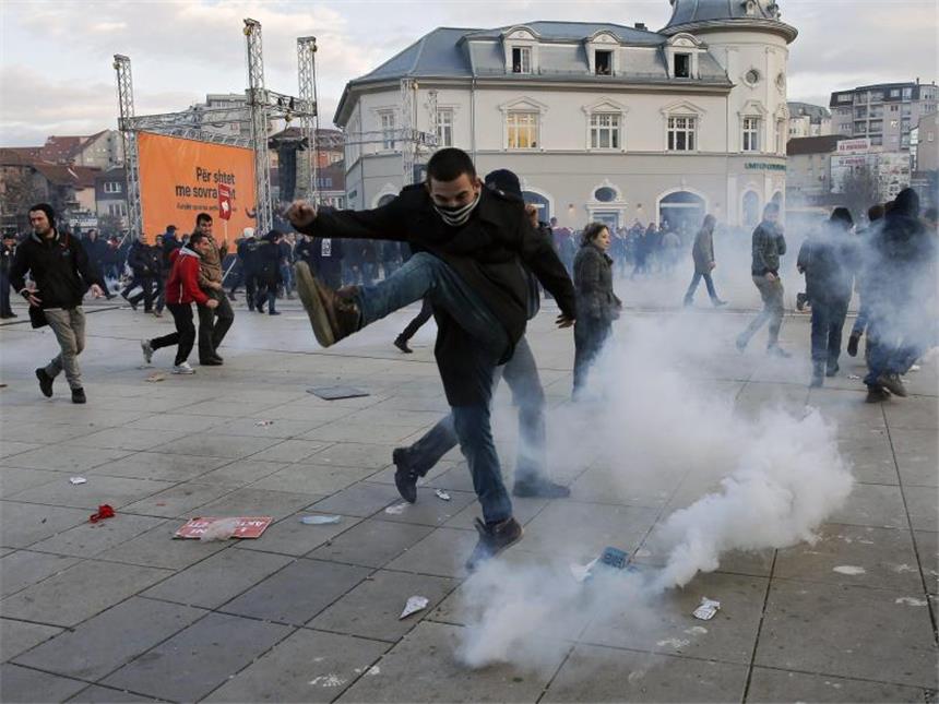 Tausende Kosovaren fordern Rücktritt der Regierung Ein Demonstrant versucht, eine Tränengasgranate wegzuschießen. Foto: Valdrin Xhemaj