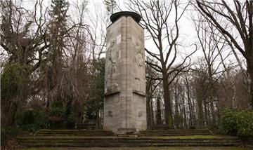 Ein Denkmal in der Form eines dreieckigen Turms mit einem auf der linken Seite abgebildeten Bergmann, der sich auf einer Hacke stützt und auf der rechten Seite eine Bergmannsfrau, die tröstend ihr Kind hält, in Bergkamen.