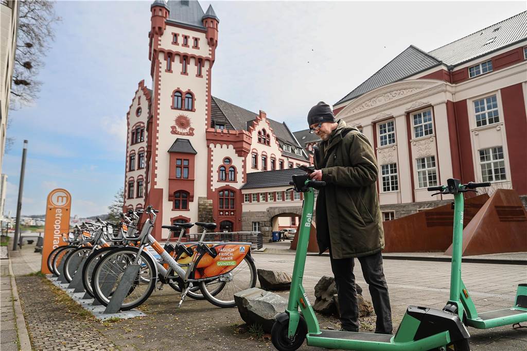 Ein Dortmunder stellt einen E-Scooter im Schatten der Hörder Burg in der Nähe des Phoenix-Sees ab.