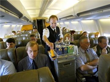 Ein Flugbegleiter der Deutschen Lufthansa AG bietet Passagieren an Bord eines Flugzeuges Getränke an.