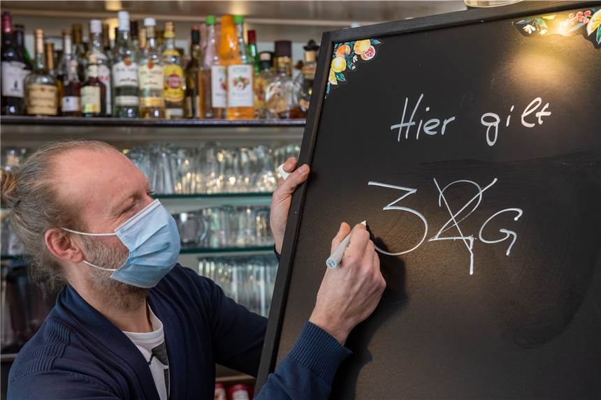„Müssen wachsam sein“: Lauterbach warnt vor Leichtfertigkeit im Corona-Frühling Ein Gastronom passt eine Informationstafel an.