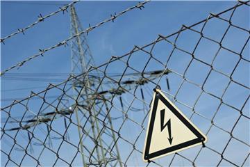 Ein Gefahrenschild für Elektrizität ist vor einer Stromtrasse zu sehen. Foto: Daniel Naupold/Archiv
