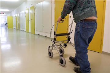 Ein Häftling im Rentenalter geht mit einem Rollator über einen Flur. Foto: Jan Woitas/Archiv