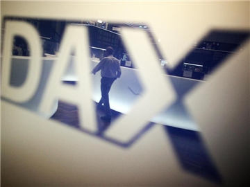 Ein Händler geht über das Parkett in der Börse in Frankfurt am Main und spiegelt sich dabei in einem Logo des Deutschen Aktienindexes (DAX). Foto: Fredrik von Erichsen