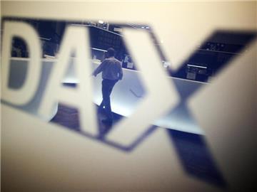 Ein Händler geht über das Parkett in der Börse in Frankfurt am Main und spiegelt sich dabei in einem Logo des Deutschen Aktienindexes (DAX). Foto: Fredrik von Erichsen