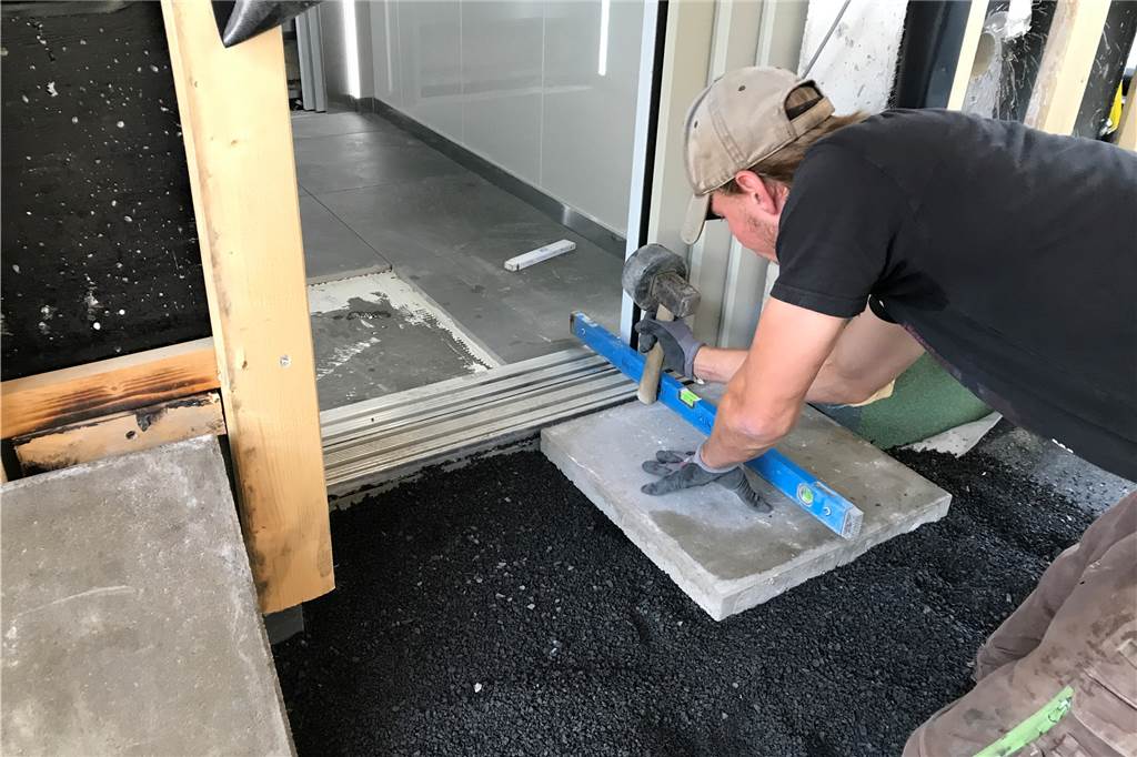 Klimaschutzsiedlung in Werne: Erste Bewohner sind schon eingezogen Ein Handwerker verlegt Bodenplatten an einem Aufzug.