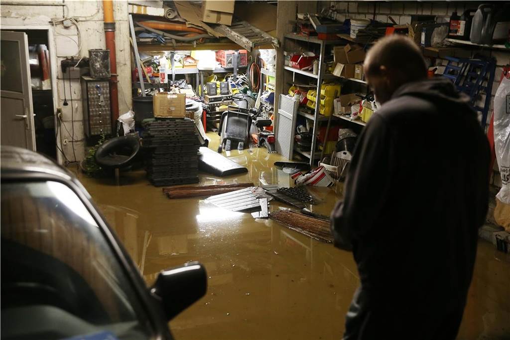 Unwetter in NRW: Chaos und Verwüstung in Hagen - Feuerwehrmann stirbt im Einsatz - Liveblog Ein Hausbesitzer steht in seiner überfluteten Garage.