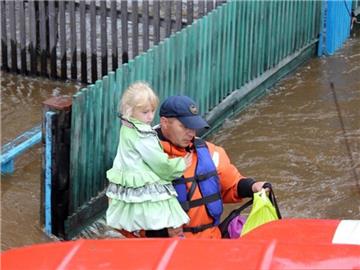 Ein Helfer trägt im Osten Russlands ein kleines Mädchen aus der Gefahrenzone. Foto: Russian Emergency Ministry Press Service