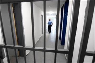 Ein Justizbeamter geht hinter einer vergitterten Tür über den Flur eines Abschiebegefängnisses. Foto: Arne Dedert/Archiv