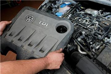 Ein Kfz-Servicetechniker in einer Autowerkstatt hält die Abdeckung eines TDI-Dieselmotors vom Typ EA189 von VW. Foto: Julian Stratenschulte
