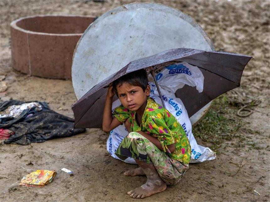 Ein Kind der Rohingyas hockt in einem Flüchtlingslager in Cox's Bazar unter einem Regenschirm. Foto: Dar Yasin