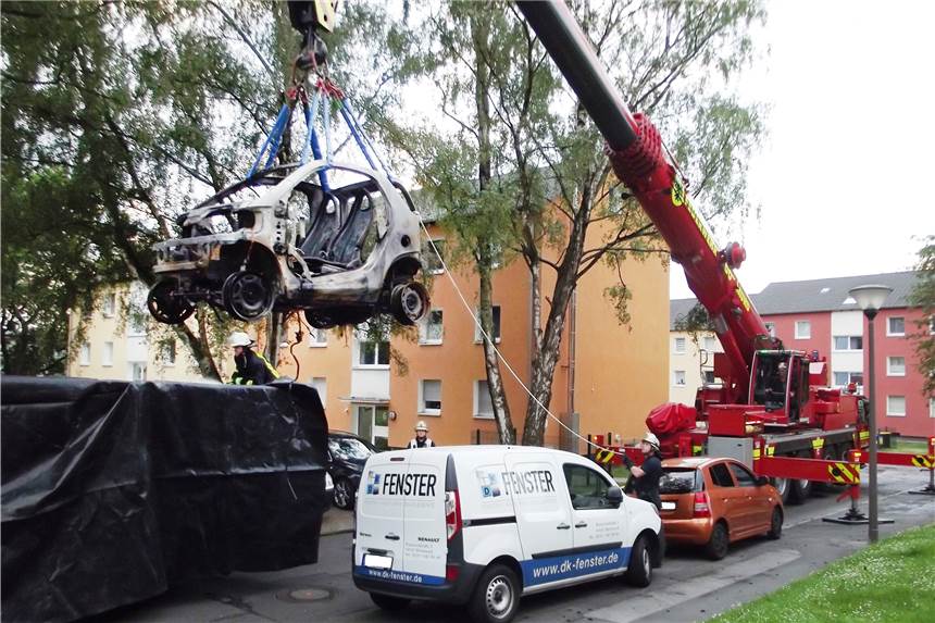 Brennende Elektroautos: Politiker fordert Feuerwehrschulungen bei Tesla Ein Kranwagen der Feuerwehr hebt ein ausgebranntes Elektroauto in einen Container.