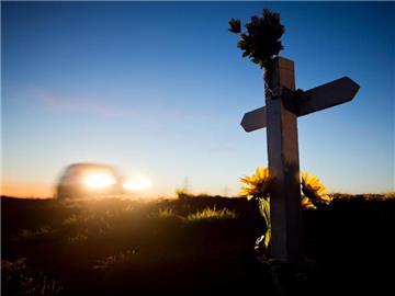 Ein Kreuz und Blumen zur Erinnerung an einen Verkehrstoten an einer Landstraße in Niedersachsen. Foto: Julian Stratenschulte