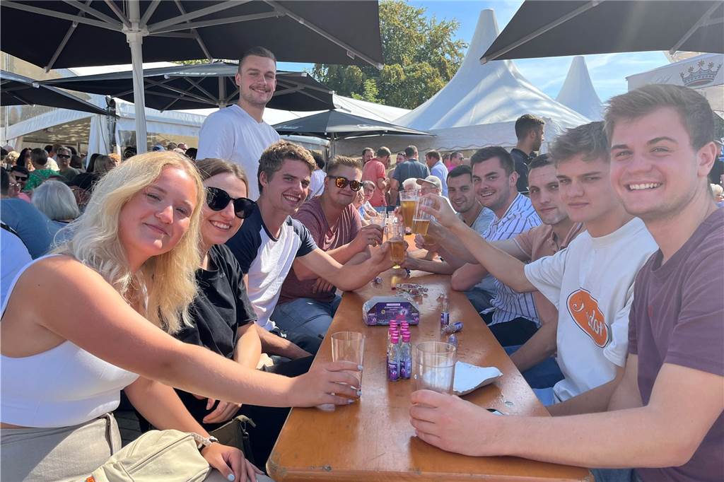 Letzter Tag auf der Kirmes : Das erleben Gäste am Montag Eine Gruppe junger Menschen trinkt Bier unter einem Sonnenschirm.