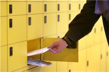 Ein Kunde leert sein Postfach bei der Post. Foto: Roland Weihrauch/Archiv