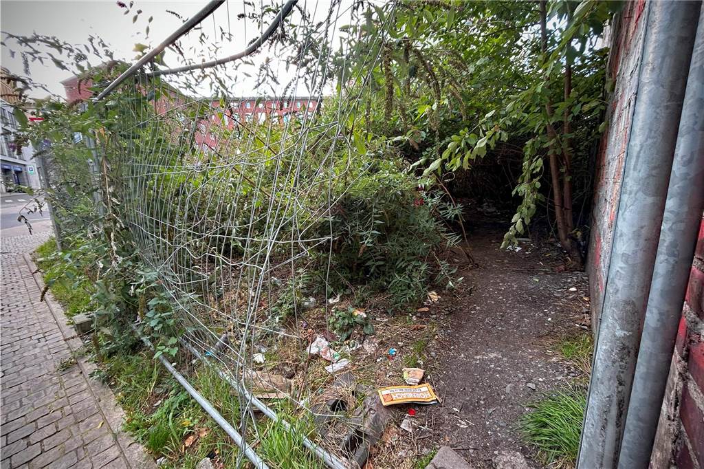 Wie ist es, neben einem Drogenkonsumraum zu leben? Ein Loch im Zaun an der Brachfläche am Grafenhof Ecke Martinstraße. Regelmäßig steigen Drogenabhängige dort durch.