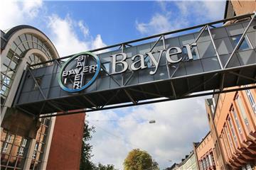 Ein Logo hängt vor dem Werk des Bayer Konzerns. Foto: Oliver Berg/Archiv