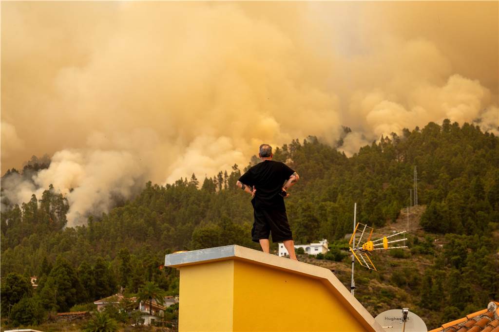 Waldbrände in Europa: Was Urlauber zurzeit wissen sollten Ein Mann beobachtete vom Dach eines Hauses aus den Waldbrand auf La Palma