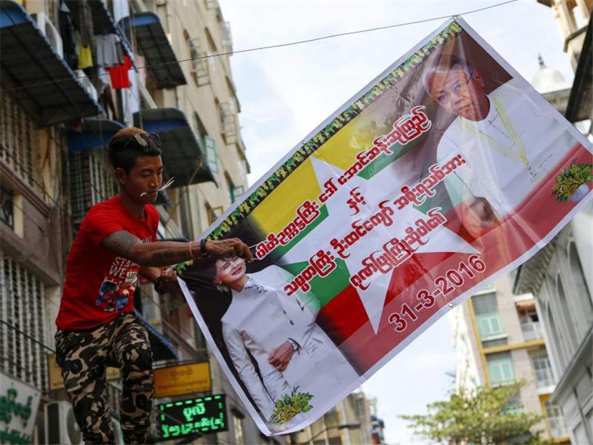 Ende der Militärmacht: Präsident in Myanmar vereidigt Ein Mann hängt in Yangon (Rangun), dem Industriezentrum des Landes, ein Poster auf, um die neue Regierung um Friedensnobelpreisträgerin Aung San Suu Kyi willkommen zu heißen. Foto: Lynn Bo Bo