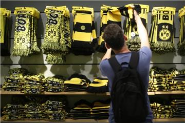 Ein Mann schaut im Fanartikel-Shop von Borussia Dortmund einen Schal an. Foto: Ina Fassbender/Archiv