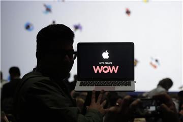 Ein Mann sitzt vor einem Laptop auf der Apple-Entwicklerkonferenz WWDC. Foto: Marcio Jose Sanchez/AP/Illustration