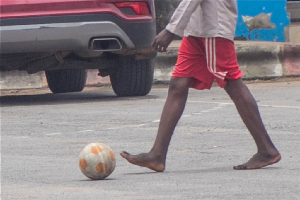 Afrikanische Bürokratie stoppt Spendenaktion aus Werne: „Wir sind verärgert“ Ein Mann spielt ohne Schuhe Fußball auf einem Schotterparkplatz: „Selbst bei einer Fußball-Akademie, die gute Fußballer weiter entwickelt und fördert, war es so, dass einige Spieler sich die Schuhe von Spielern anderer Mannschaften leihen mussten oder mit zwei verschiedenen Schuhen aufliefen“, erklärt Dietmar Wurst.