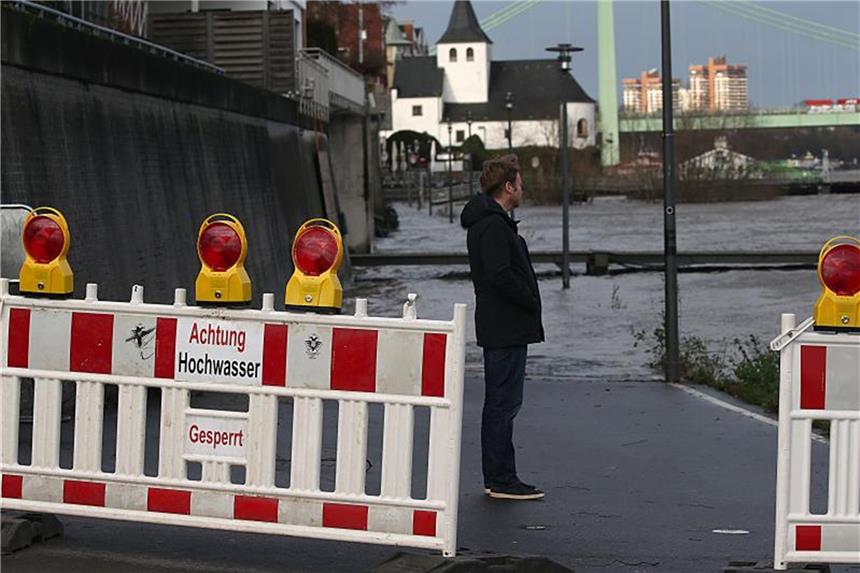 Köln und Düsseldorf für steigende Pegelstände gerüstet Ein Mann steht in Köln am Rheinufer hinter einer Absperrung. Foto: Oliver Berg