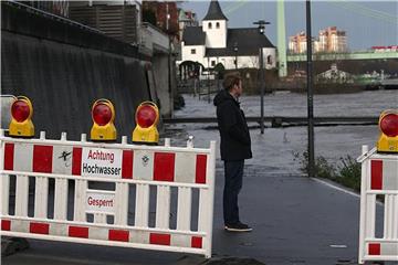 Ein Mann steht in Köln am Rheinufer hinter einer Absperrung. Foto: Oliver Berg