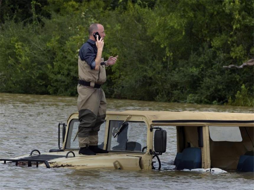 Hochwasser in Texas: Furcht vor Bakterien und Chemikalien Ein Mann telefoniert auf der Kühlerhaube eines Fahrzeuges, das in einer überfluteten Straße in Houston steht. Foto: Carol Guzy