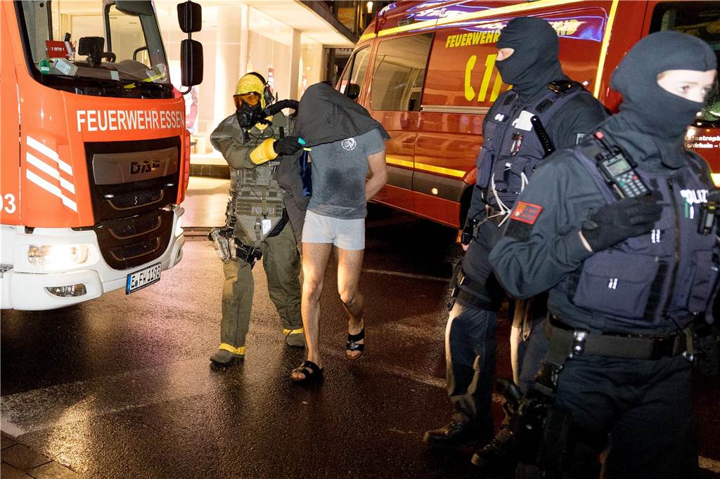 Ein Mann wird von einem Beamten des Spezialeinsatzkommandos (SEK) mit Schutzmaske in Gewahrsam genommen. Anti-Terror-Ermittler haben in Castrop-Rauxel im nördlichen Ruhrgebiet einen 32-Jährigen und seinen sechs Jahre jüngeren Bruder (Foto) festgenommen, der einen islamistischen Anschlag vorbereitet haben soll. 