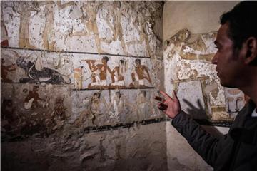 Ein Mitarbeiter der Ausgrabungen deutet auf die Wandmalereien in einem neu entdeckten Grab in der Nähe der Cheops-Pyramiden. Foto: Fayed El-Geziry