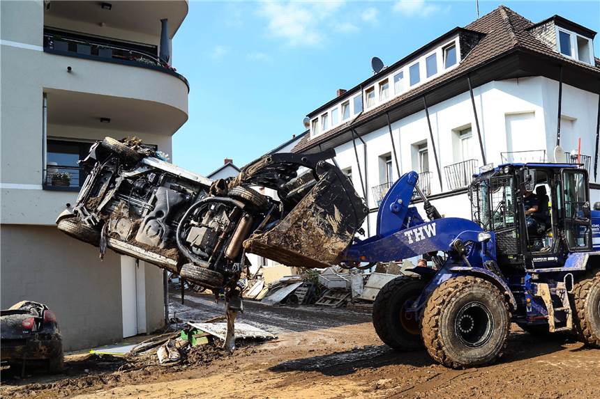 THW-Helfer in Flutgebieten beschimpft und mit Müll beworfen Ein Mitarbeiter des Technischen Hilfswerks (THW) transportiert bei mit einem Schauffelbagger ein Autowrack.