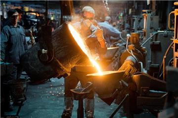 Ein Mitarbeiter gießt flüssiges Gusseisen im Werk eines Autozulieferers. Foto: Julian Stratenschulte/Archiv