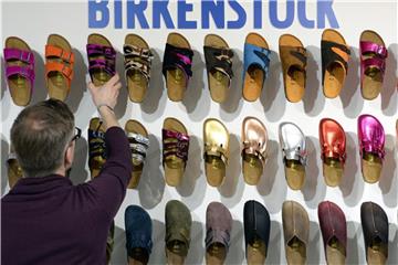 Ein Mitarbeiter sortiert 2014 auf einer Modemesse Schuhe von "Birkenstock". Foto: Soeren Stache