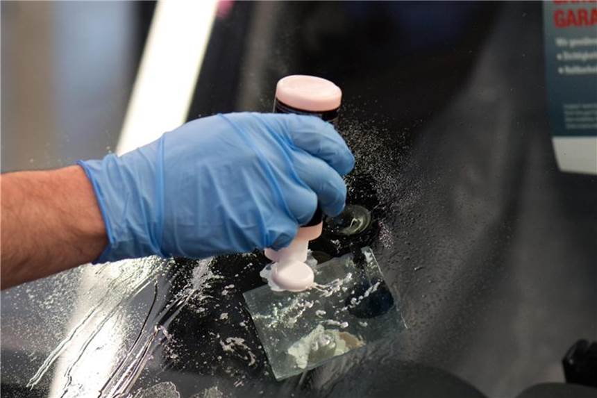 Ein Mitarbeiter von Carglass repariert einen Steinschlagschaden in der Frontscheibe eines Autos. Foto: Arno Burgi