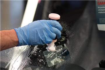 Ein Mitarbeiter von Carglass repariert einen Steinschlagschaden in der Frontscheibe eines Autos. Foto: Arno Burgi