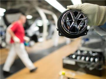 Ein Mitarbeiter zeigt in Wolfsburg ein Volkswagen-Logo. Foto: Foto: Julian Stratenschulte