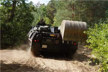 Ein Panzer der Bundeswehr schneidet eine Schneise in den Wald, damit die Feuerwehrleute besser an die Glutherde herankommen. Foto: Christian Pörschmann