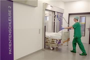 Ein Pfleger schiebt ein Bett in den Operationstrakt. Foto: Patrick Seeger/Illustration