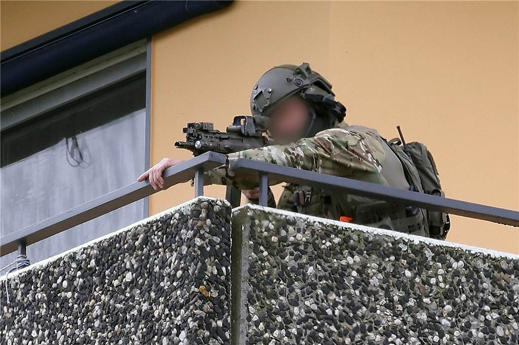 Ein Polizeibeamter in Spezialausrüstung steht auf einem Balkon und zielt mit einer Waffe. Bei einer Explosion in einem Hochhaus in Ratingen am Donnerstagvormittag wurden mehrere Menschen verletzt - darunter auch Polizisten und Einsatzkräfte der Feuerwehr. Das erfuhr die Deutsche Presse-Agentur aus Polizeikreisen.