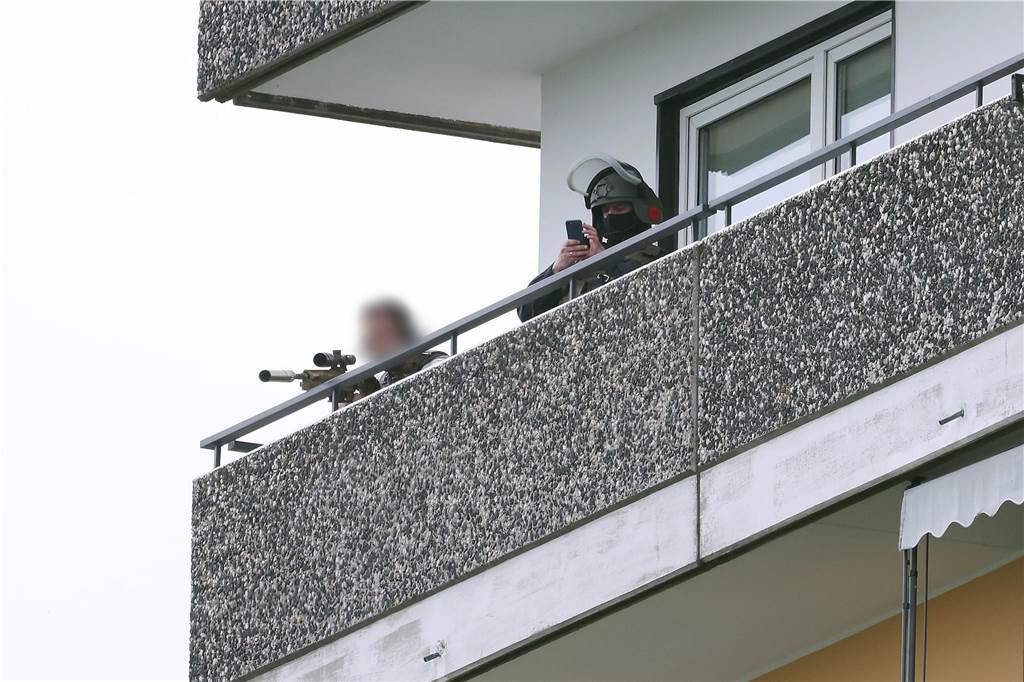 Ein Polizeibeamter in Spezialausrüstung steht auf einem Balkon neben einem Kollegen und zielt mit einer Waffe. Bei einer Explosion in einem Hochhaus in Ratingen am Donnerstagvormittag wurden mehrere Menschen verletzt - darunter auch Polizisten und Einsatzkräfte der Feuerwehr. Das erfuhr die Deutsche Presse-Agentur aus Polizeikreisen.