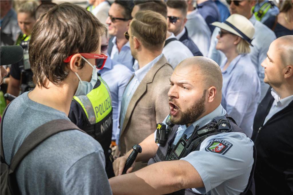 Ein Polizeibeamter schiebt einen Gegendemonstranten zurück.