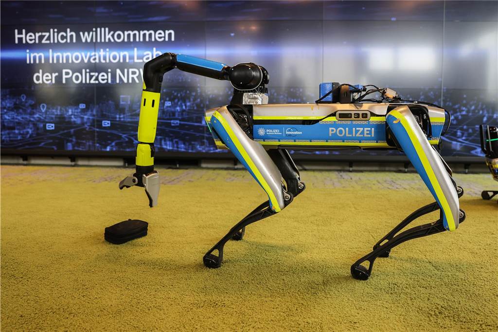 Eine Hundeschule für Roboter: Wie die NRW-Polizei „Spot“ anlernt Ein Polizeiroboter hebt in einer Trainingssituation im Innovation Lab der Polizei eine Tasche auf.